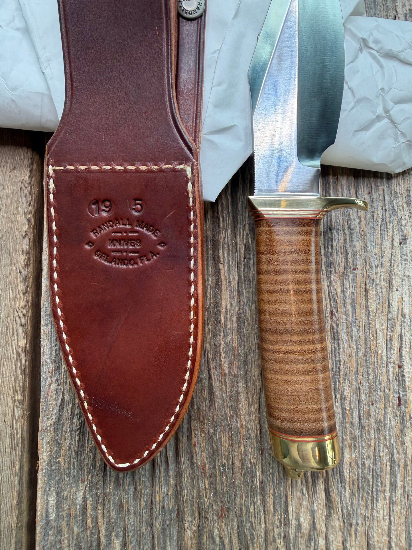 New in Paper Randall Model 19-5 Bushmaster with a Leather handle. Carbon blade, Brass single hilt. Brown leather sheath.