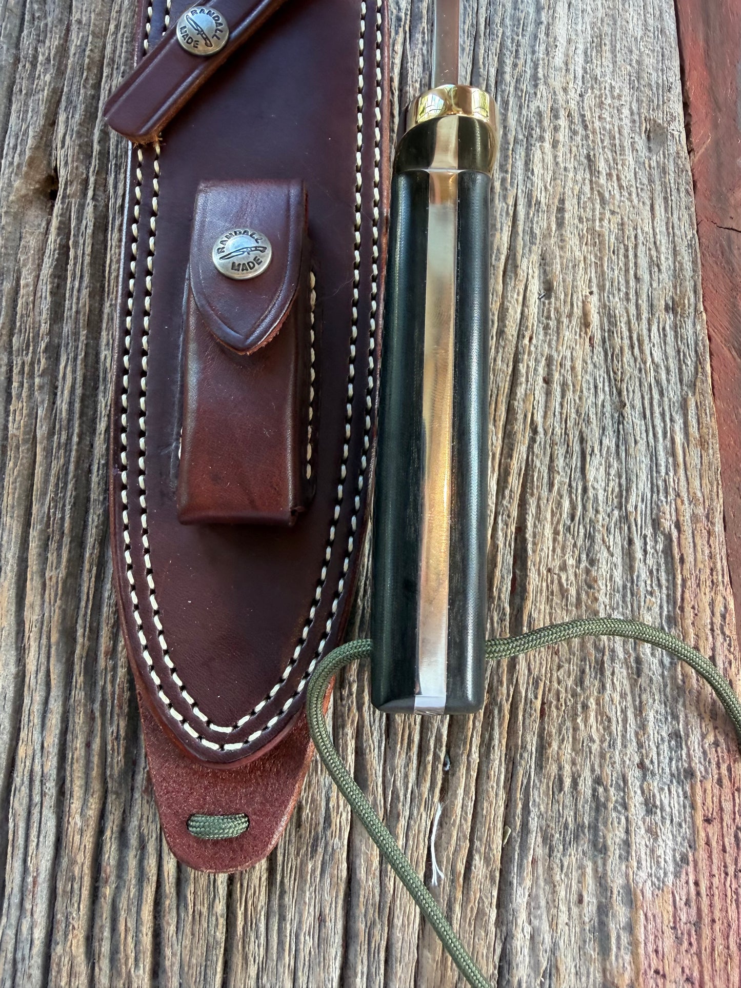 Randall Model 14-7.5 with a Black Micarta finger grooved handle. Stainless steel blade, Brass double hilt brown leather sheath.