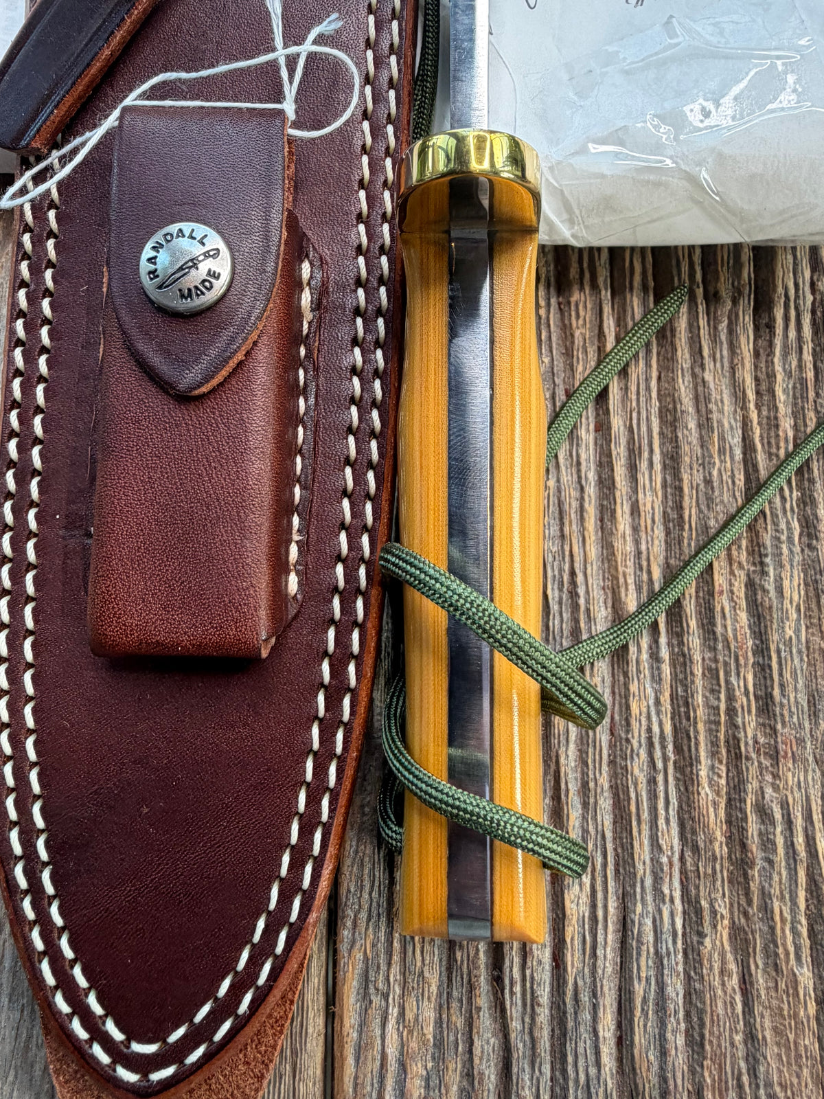 Randall Model 14-7.5 with a Yellow Micarta single finger handle. Carbon steel blade, brass double hilt, brown leather sheath, Lanyard.