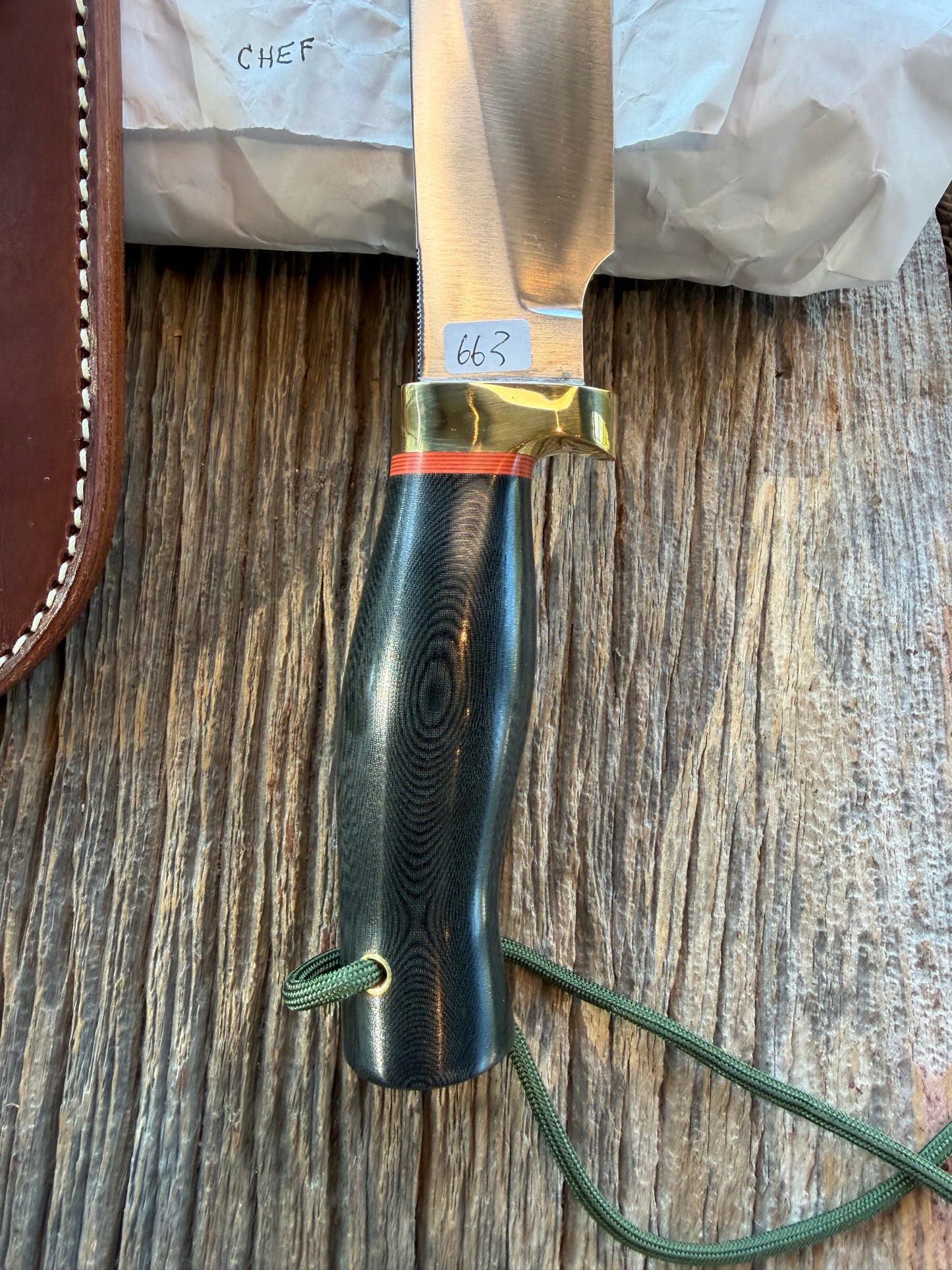 New in Paper Randall Chef’s Knife. Black Micarta in Brass with red spacers. Natural end, stainless steel blade and a lanyard.