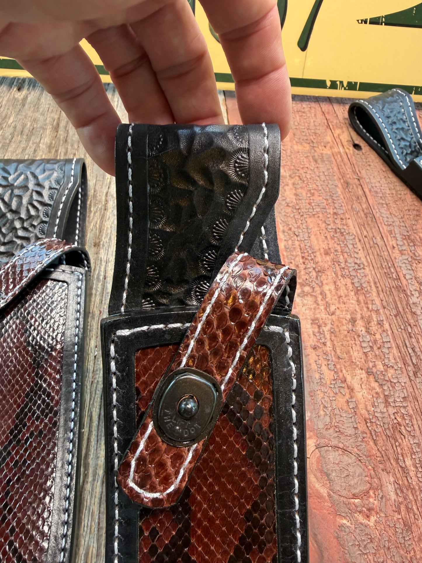 New pair of Randall Model 12-11 Large Sasquatch and 12-8 Small Sasquatch Sheath in Exotic Brown Python Snake on black leather from Treeman with a black Canteen snap. Hand tooled belt loop. Deviated white stitching. Killer sheath.