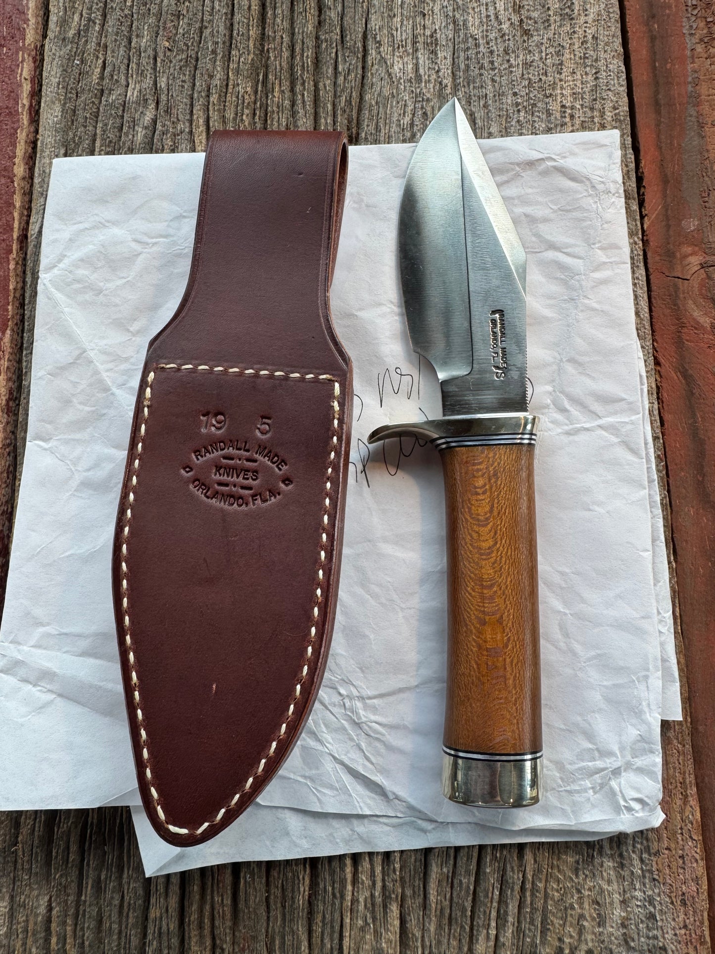 New in Paper Randall Model 19-5 Bushmaster with an Oak handle. SS blade, Nickel silver single hilt. Lanyard. Brown leather sheath.