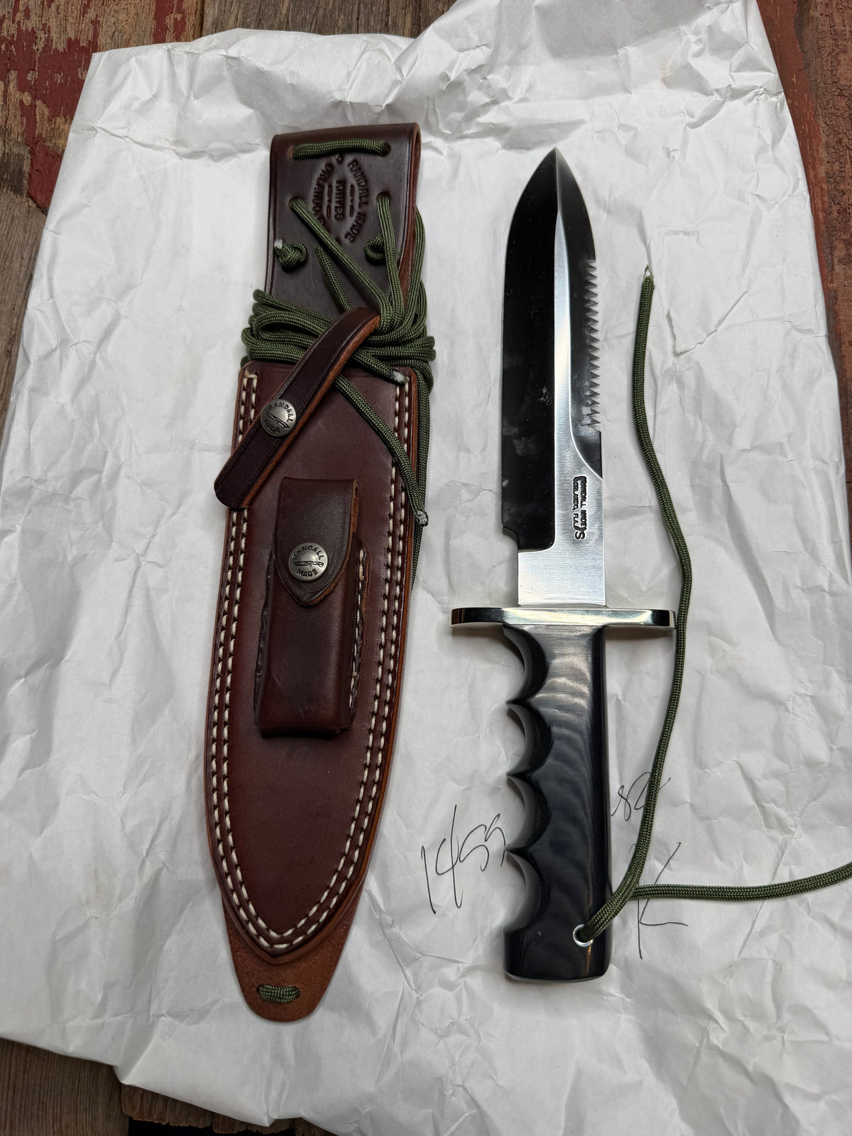 Randall Model 14-7.5 with a Black Micarta finger grooved handle. Stainless steel blade, Nickel double hilt brown leather sheath, Sawteeth, Lanyard.