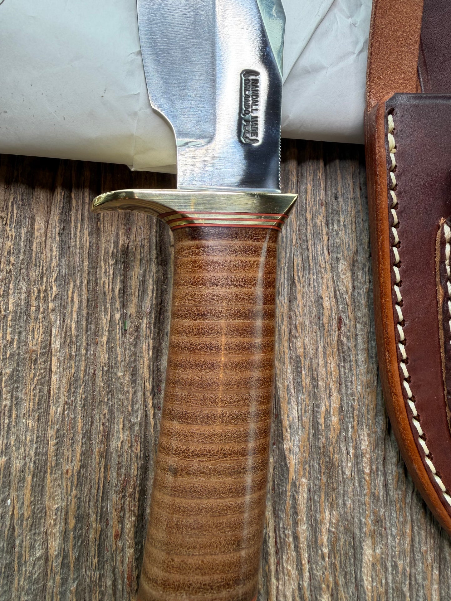 New in Paper Randall Model 19-5 Bushmaster with a Leather handle. Carbon blade, Brass single hilt. Brown leather sheath.