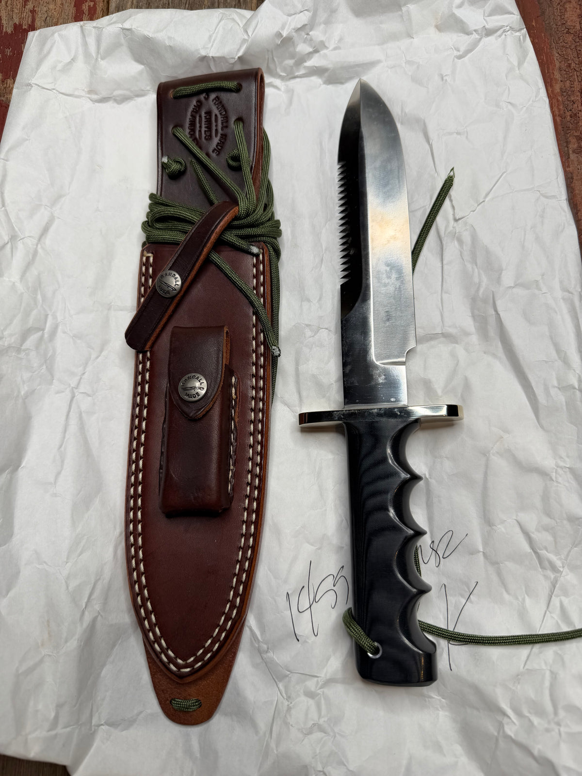 Randall Model 14-7.5 with a Black Micarta finger grooved handle. Stainless steel blade, Nickel double hilt brown leather sheath, Sawteeth, Lanyard.