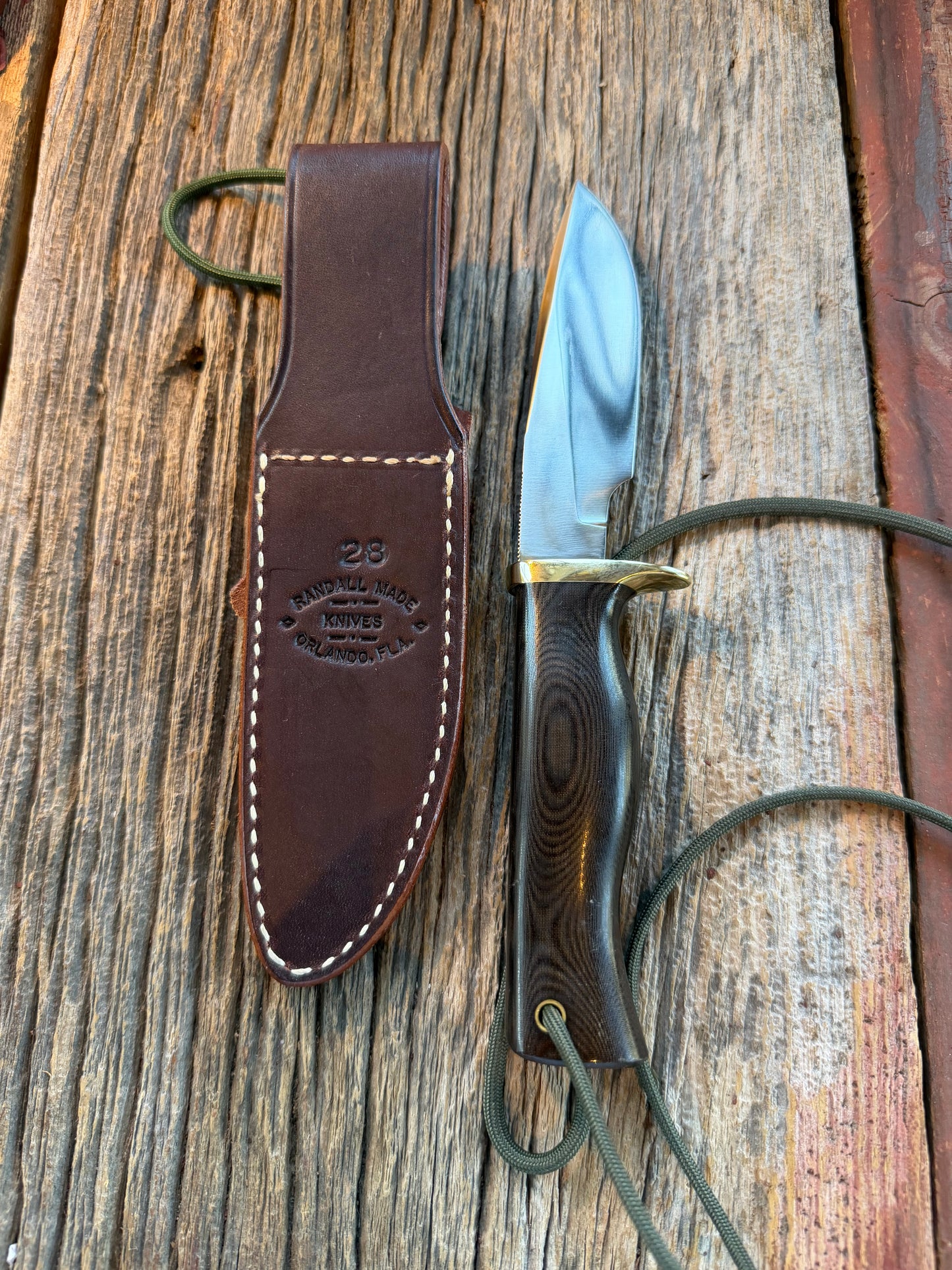 Nice Randall Model 28 Woodsman in Black Micarta. SS blade, brass single hilt. Lanyard. Brown leather sheath.