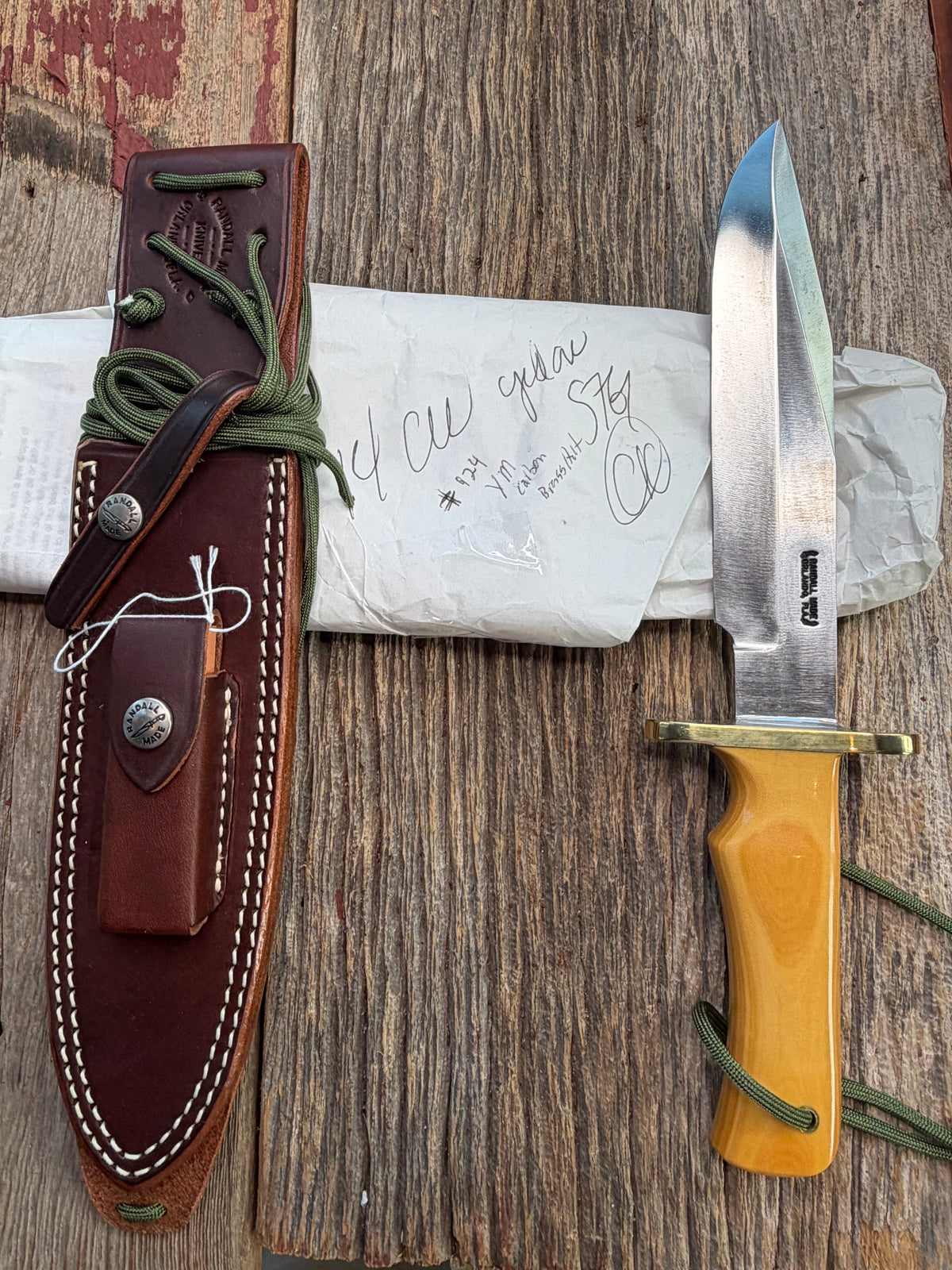 Randall Model 14-7.5 with a Yellow Micarta single finger handle. Carbon steel blade, brass double hilt, brown leather sheath, Lanyard.