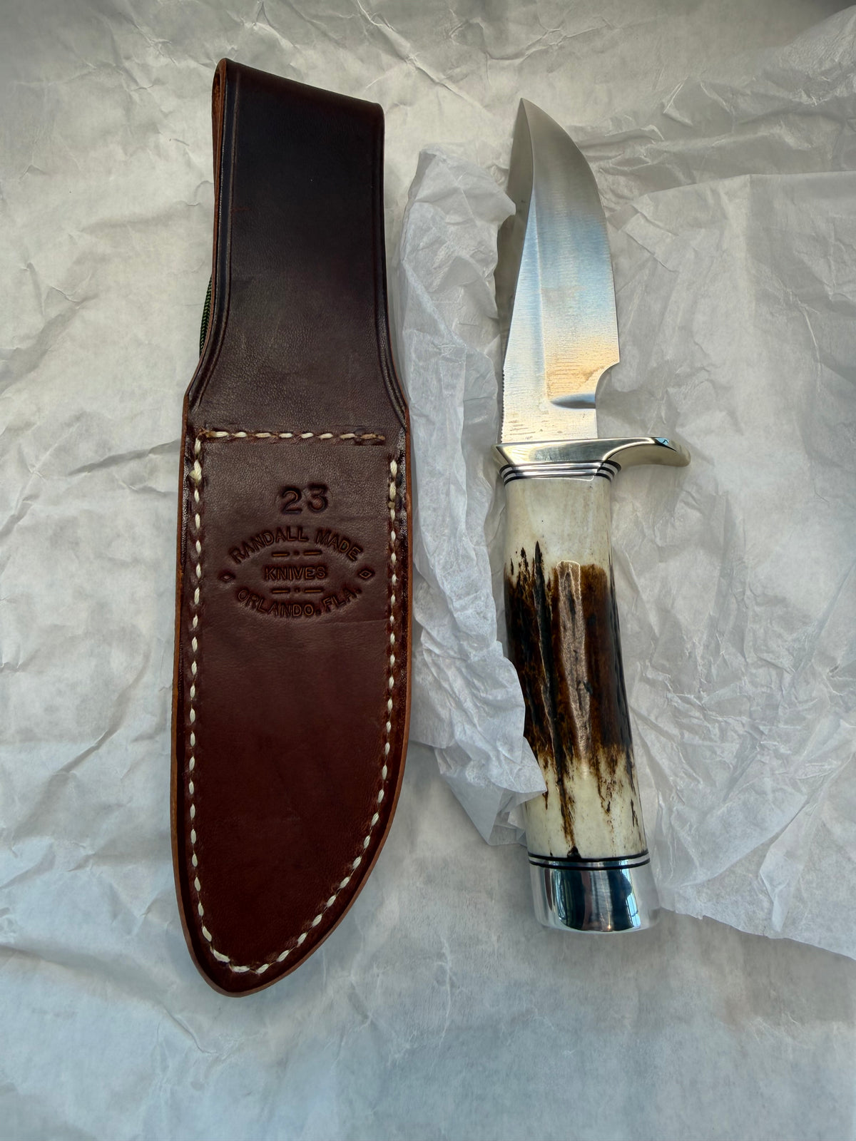 New in paper Randall Model 23 Game Master in a nice fat piece of Stag. Stainless steel blade, Nickel silver hilt, Black and Aluminum spacers and Brown leather sheath.