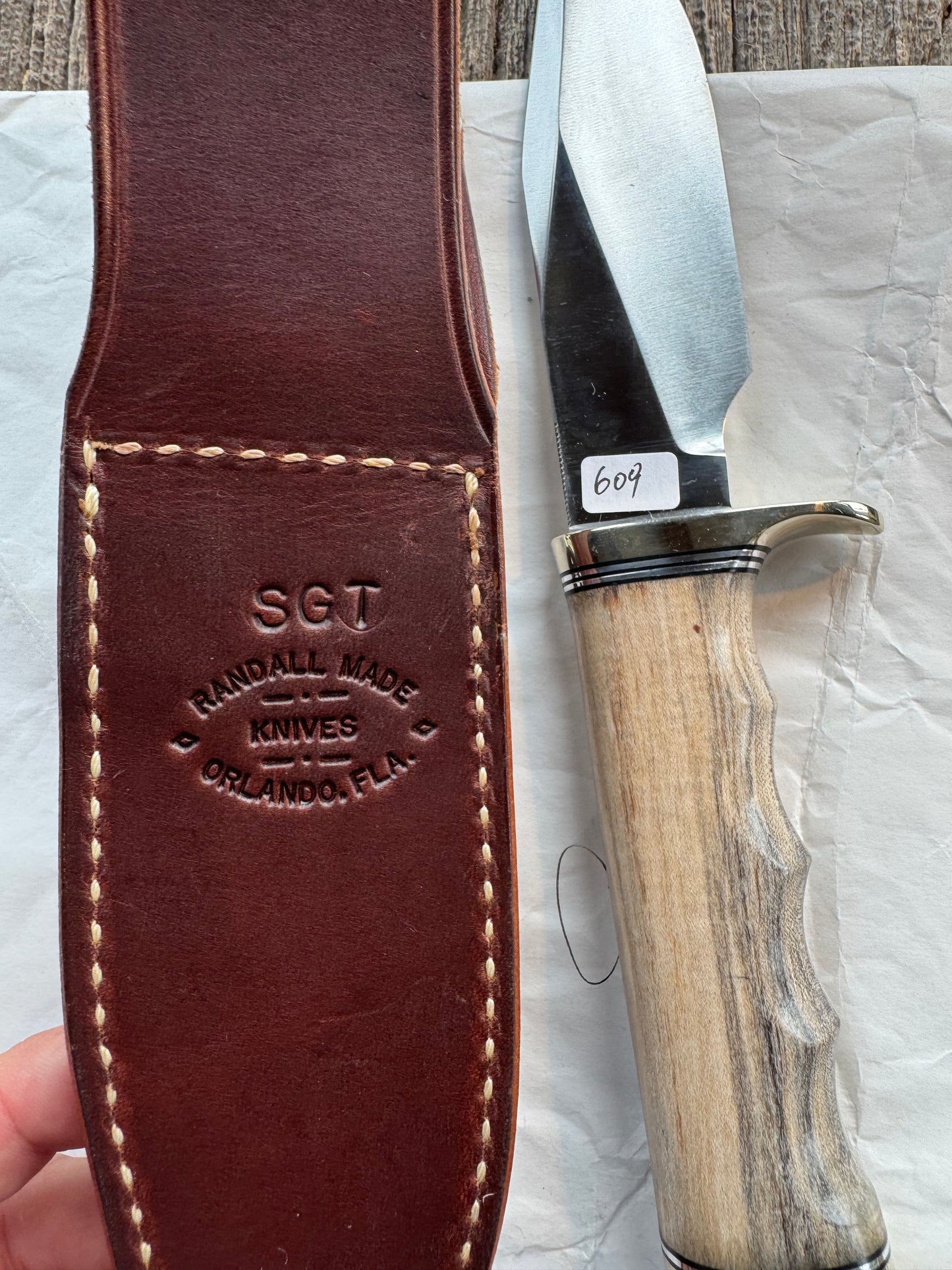 New in Paper Randall Non Catalog Model Sergeants Special, Maple handle with finger grooves. Carbon blade, Nickel silver single hilt and butt cap. Brown leather sheath.
