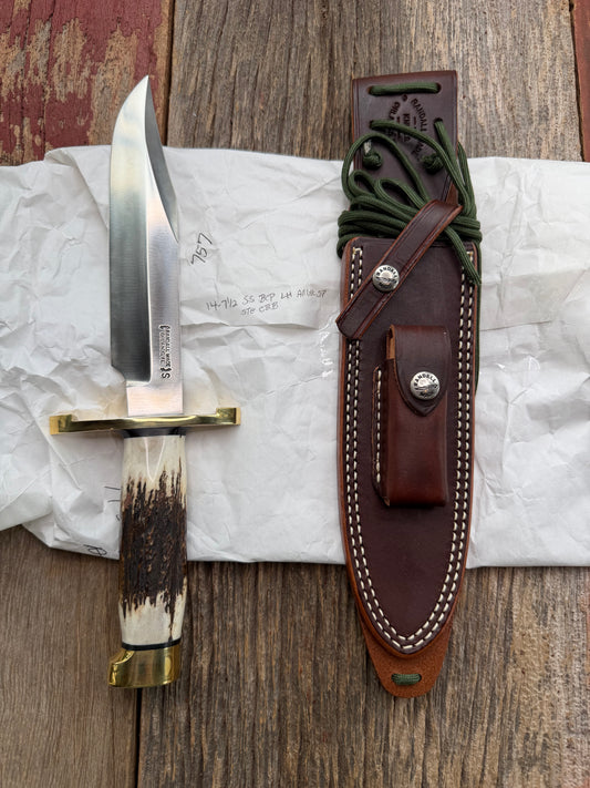 New in paper fresh from the Shop. Randall Knife Model 14-7.5 Big. Nice piece of Stag, Gorgeous Brass Lugged hilt and brass crows beak butt cap. Single black spacer. Stainless steel.