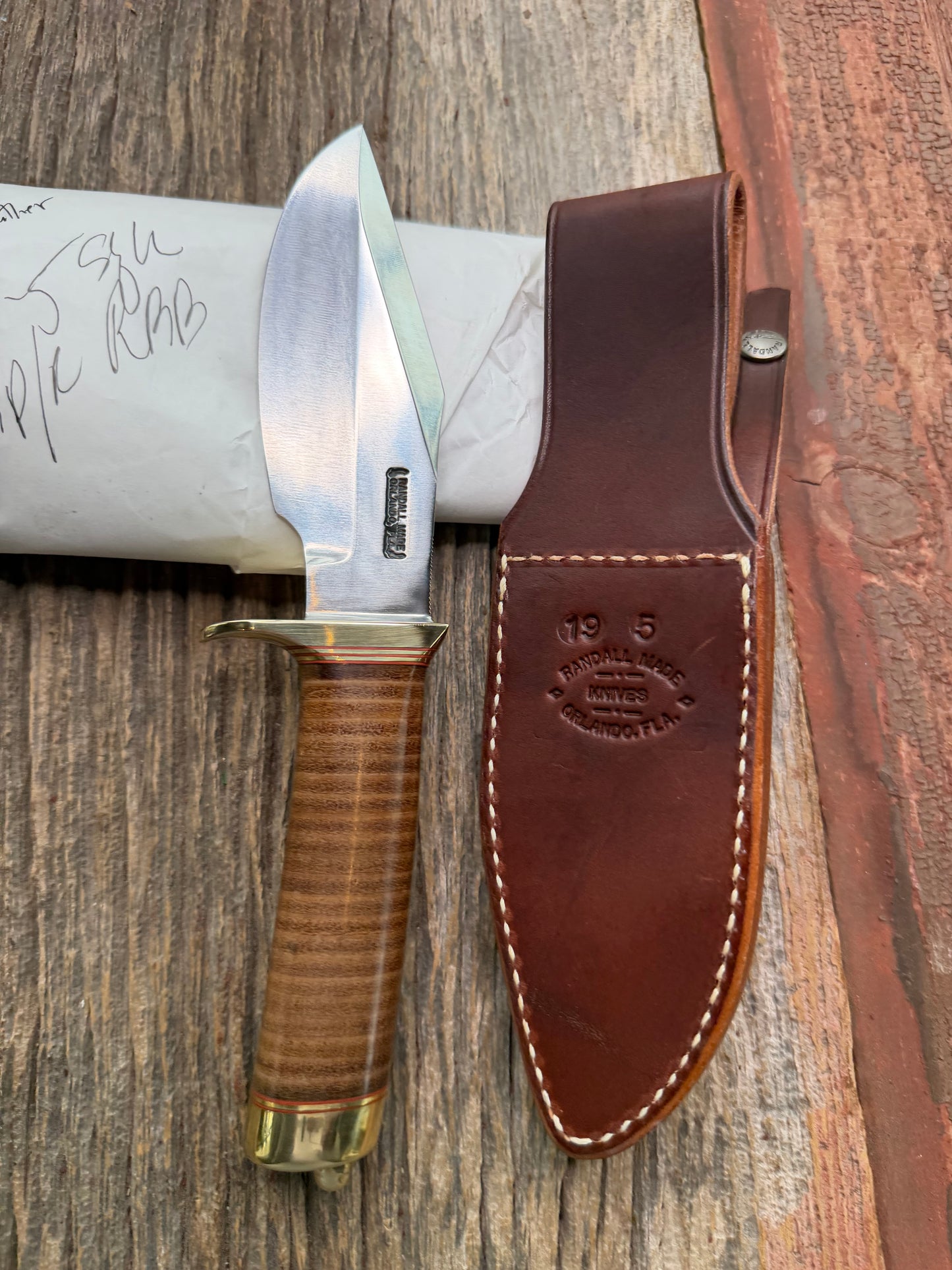 New in Paper Randall Model 19-5 Bushmaster with a Leather handle. Carbon blade, Brass single hilt. Brown leather sheath.