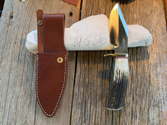 New in Paper Randall Model 19-5 Bushmaster with a Stag handle. Carbon blade, Nickel silver single hilt. Brown leather sheath.