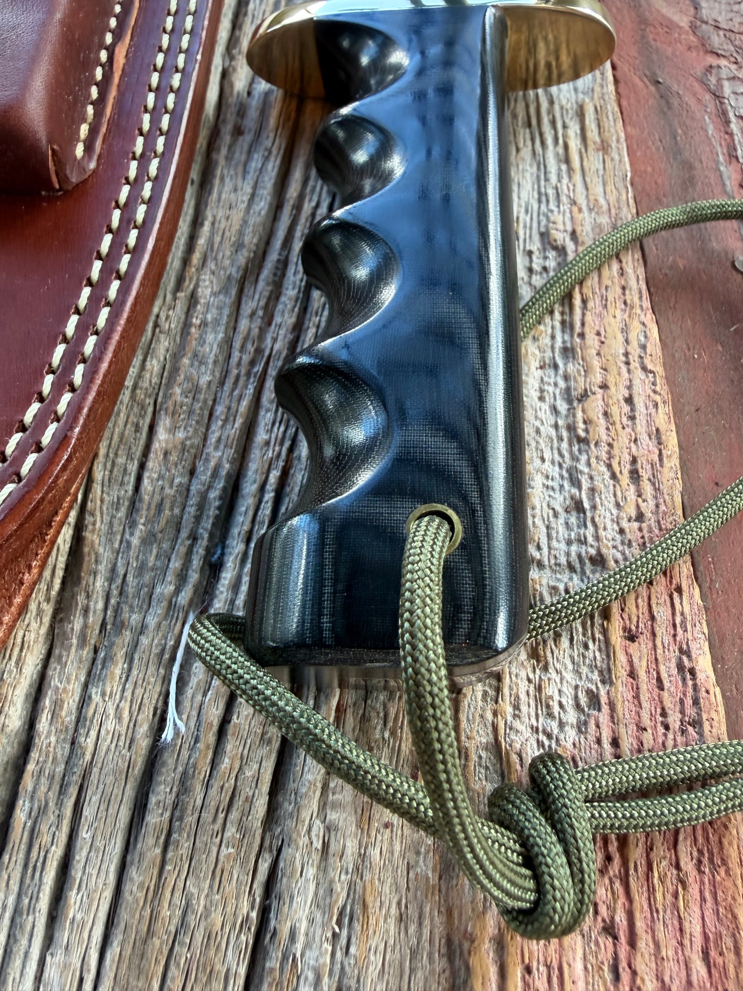 Randall Model 14-7.5 with a Black Micarta finger grooved handle. Carbon steel blade, Brass double hilt brown leather sheath.