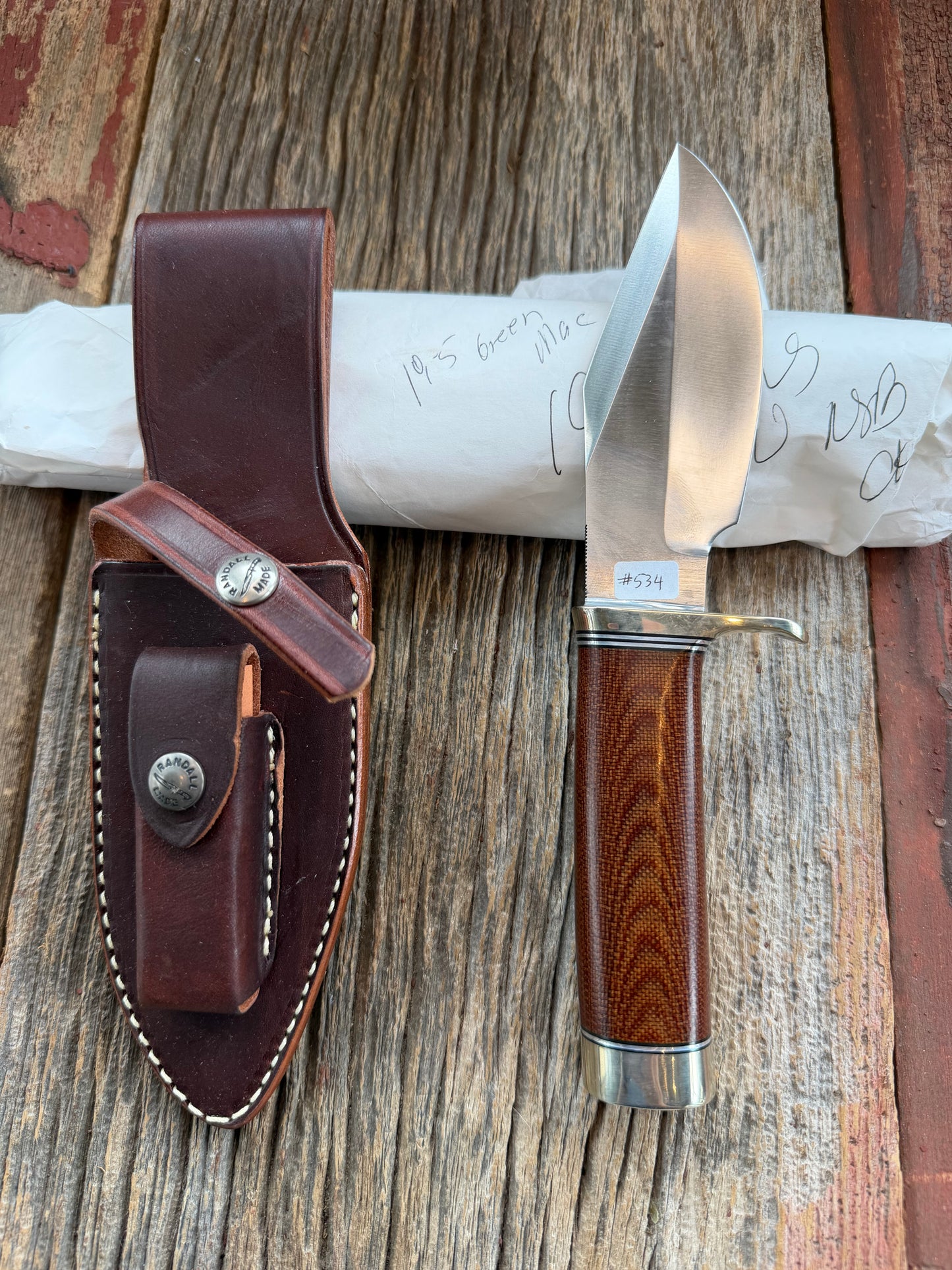 New in Paper Randall Model 19-5 Bushmaster with an Brown Micarta handle. SS blade, Nickel silver single hilt. Lanyard. Brown leather sheath.