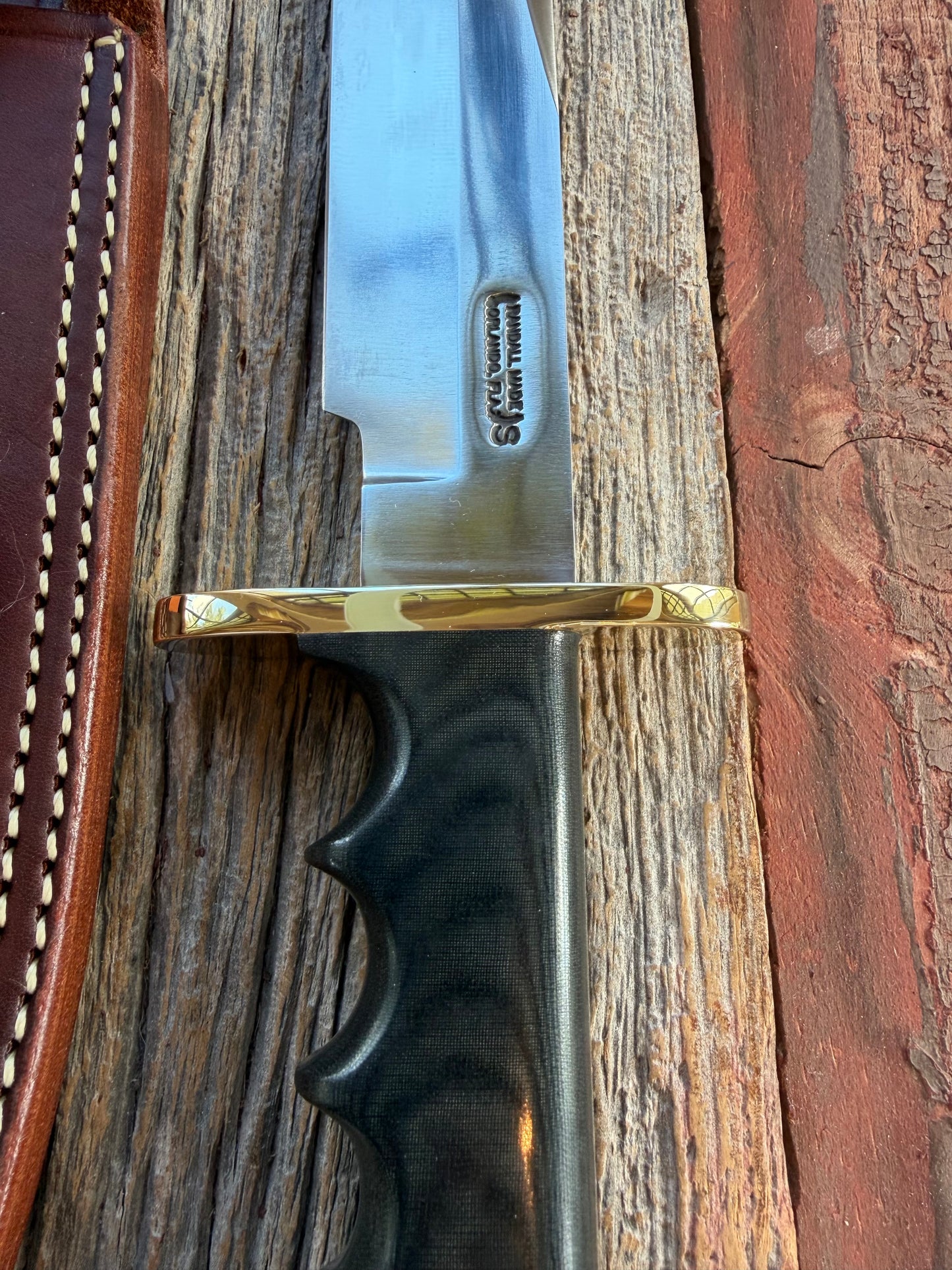 Randall Model 14-7.5 with a Black Micarta finger grooved handle. Stainless steel blade, Brass double hilt brown leather sheath.