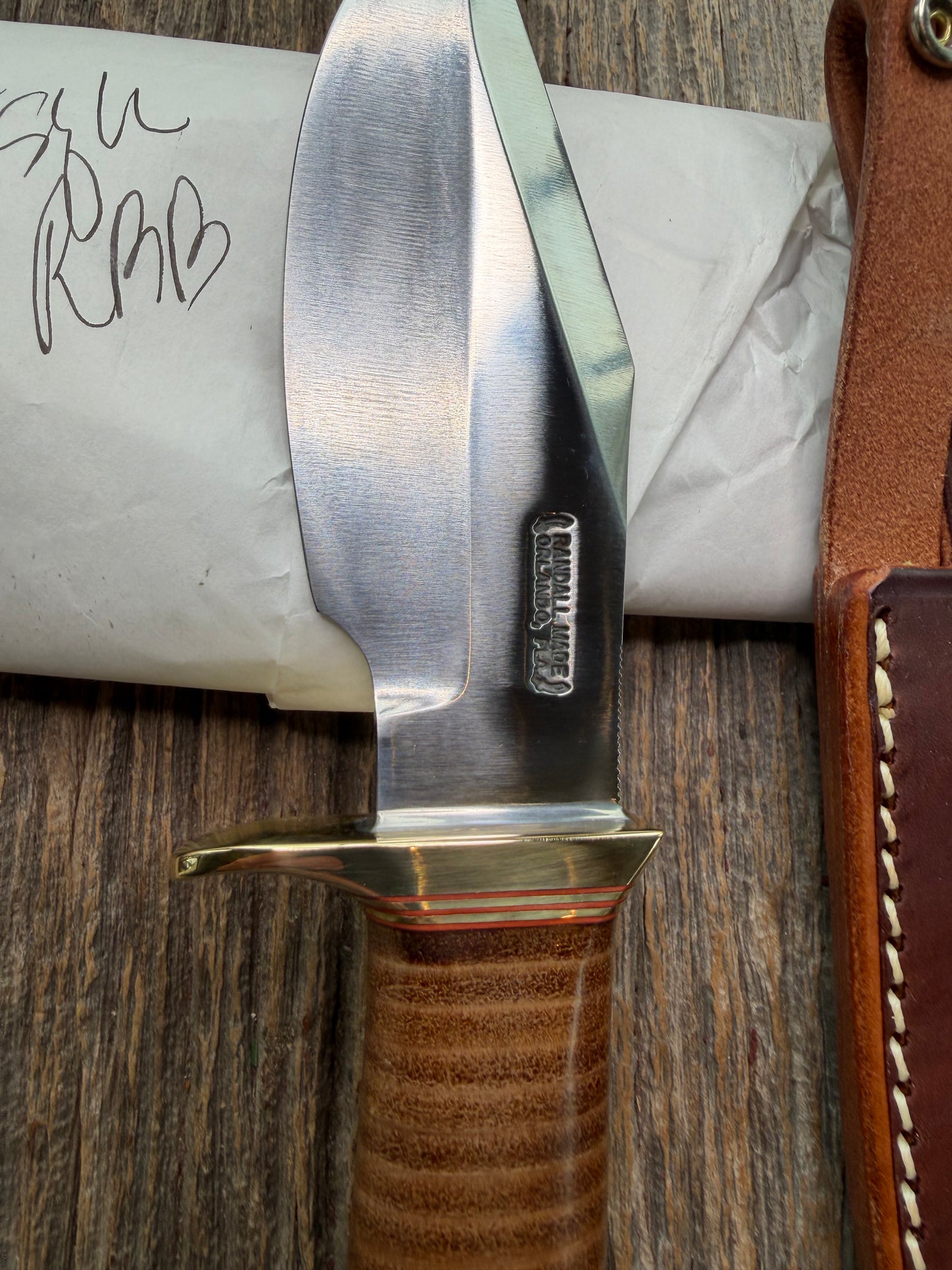 New in Paper Randall Model 19-5 Bushmaster with a Leather handle. Carbon blade, Brass single hilt. Brown leather sheath.