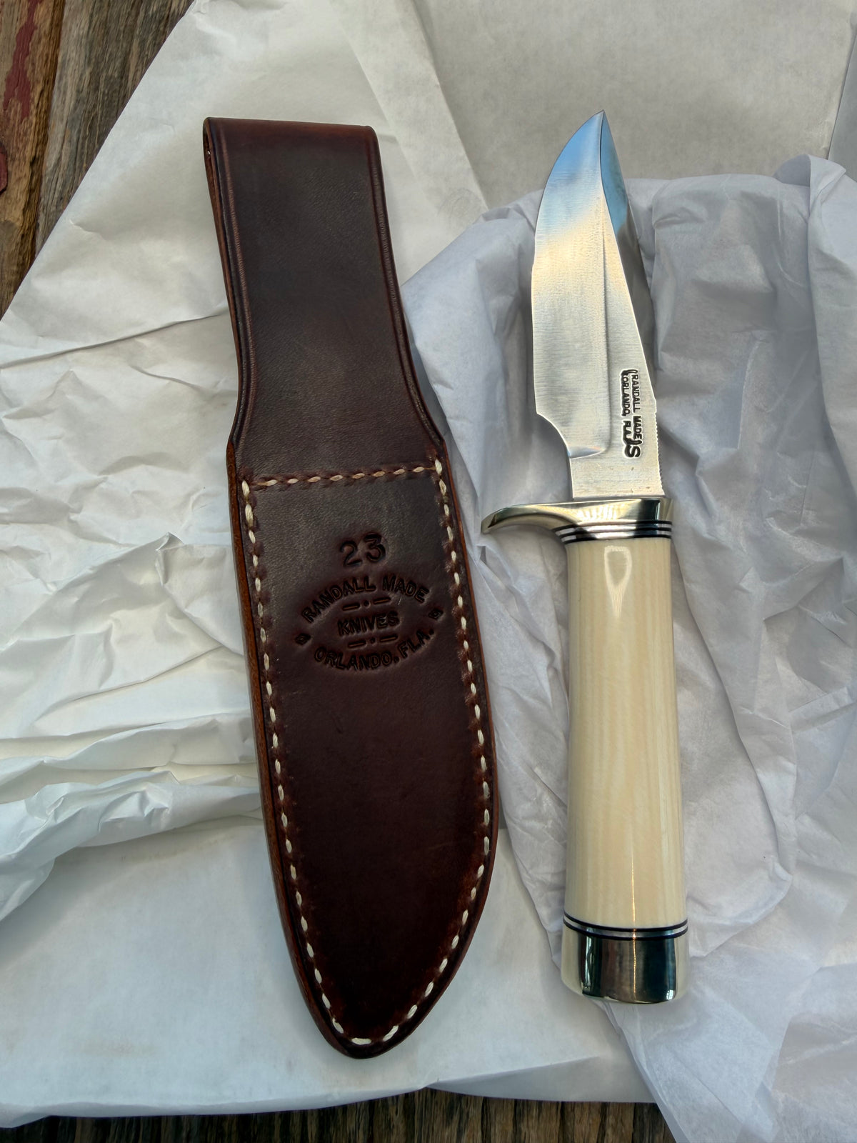 New in paper Randall Model 23 Game Master in dealer supplied Resin, Stainless steel blade, Nickel silver hilt and butt cap, Black and Aluminum spacers and Brown leather sheath.