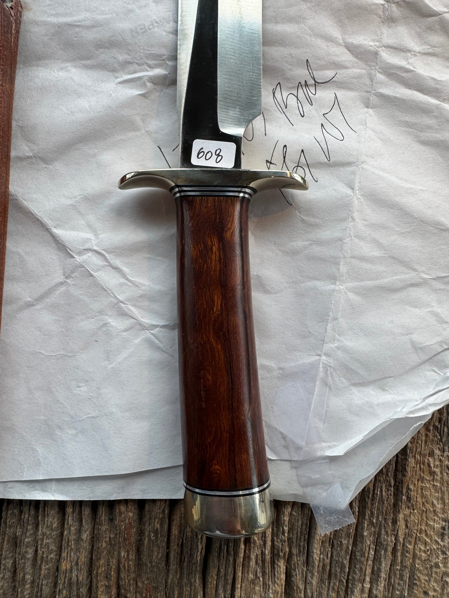 New in Paper Randall Model 1-7 Stainless steel blade, Nickel silver hilt and butt cap. Brown leather sheath. Burl wood handle.
