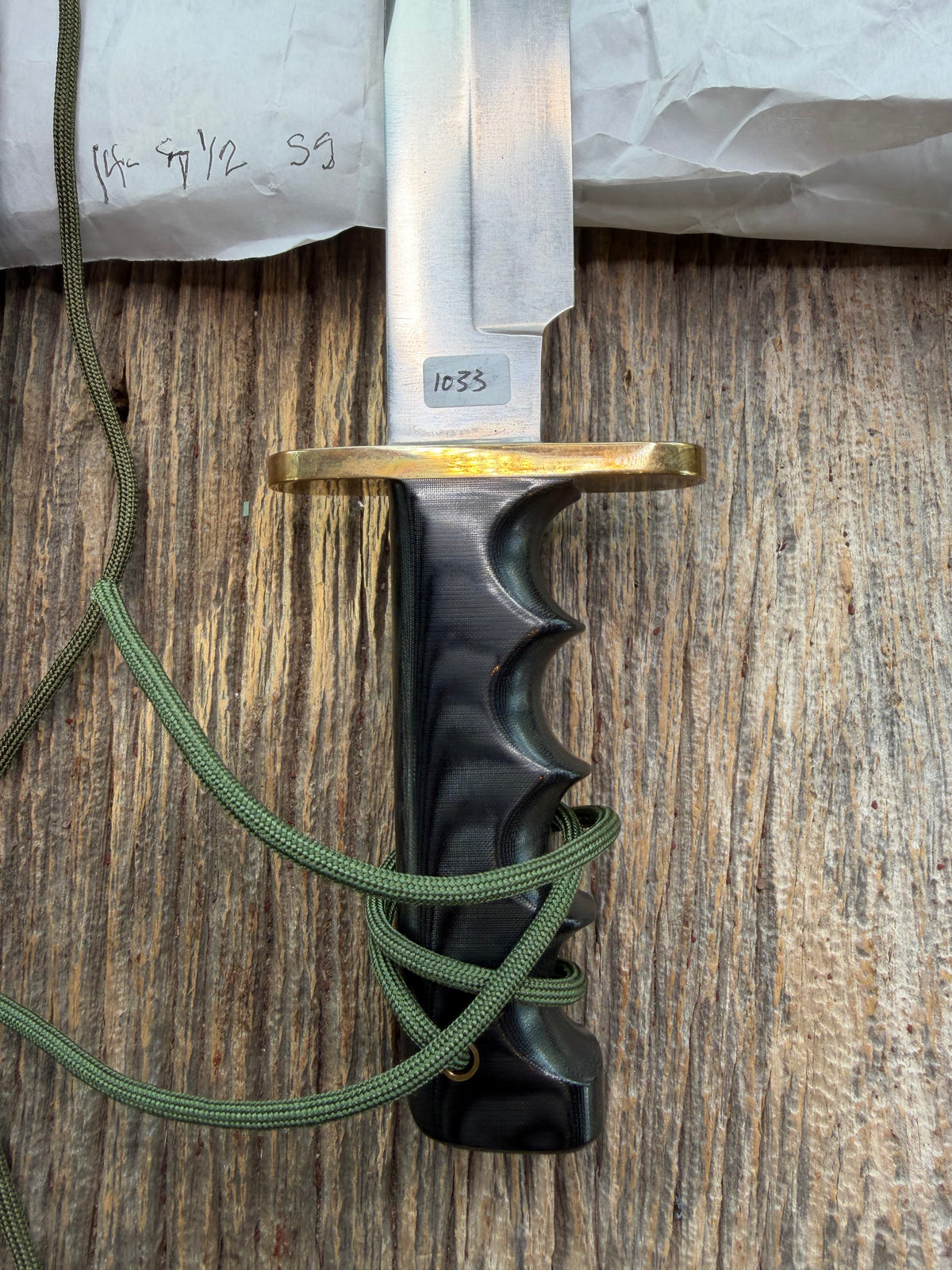 Randall Model 14-7.5 with a Black Micarta finger grooved handle. Stainless steel blade, brass double hilt brown leather sheath, Lanyard.