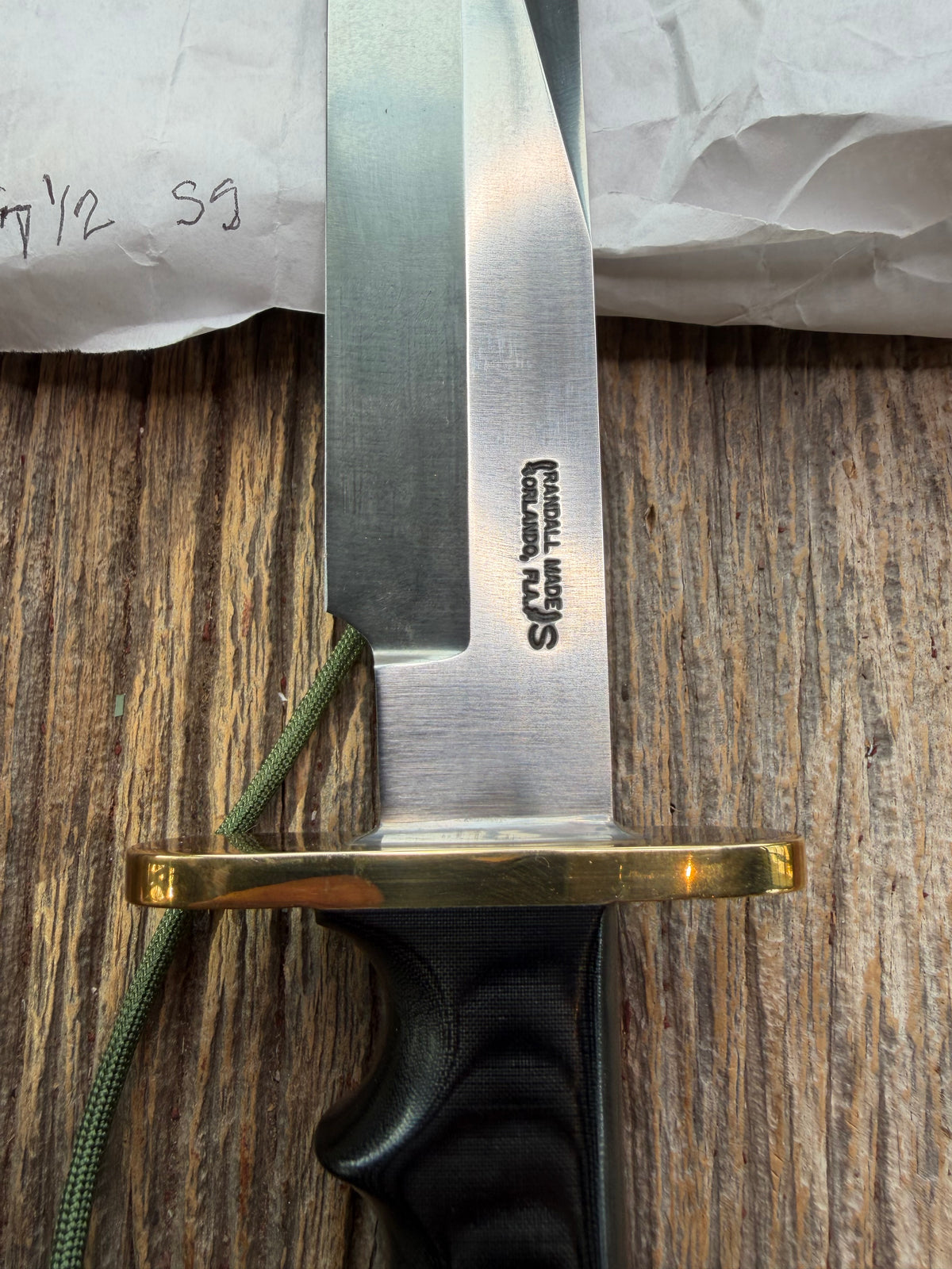 Randall Model 14-7.5 with a Black Micarta finger grooved handle. Stainless steel blade, brass double hilt brown leather sheath, Lanyard.