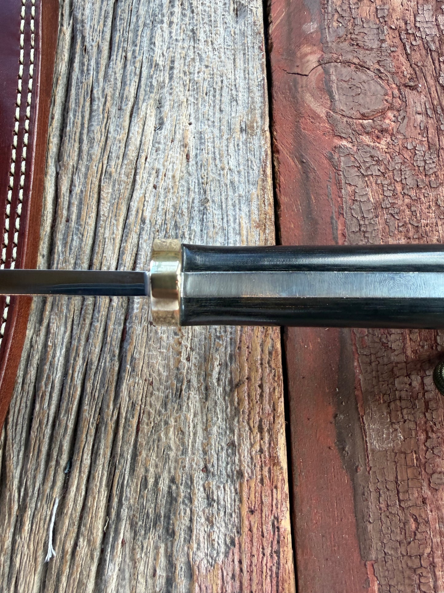 Randall Model 14-7.5 with a Black Micarta finger grooved handle. Carbon steel blade, Brass double hilt brown leather sheath.