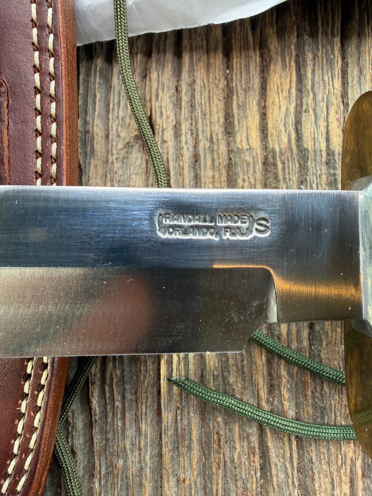 Randall Model 14-7.5 with a Black Micarta finger grooved handle. Stainless steel blade, brass double hilt brown leather sheath, Lanyard.