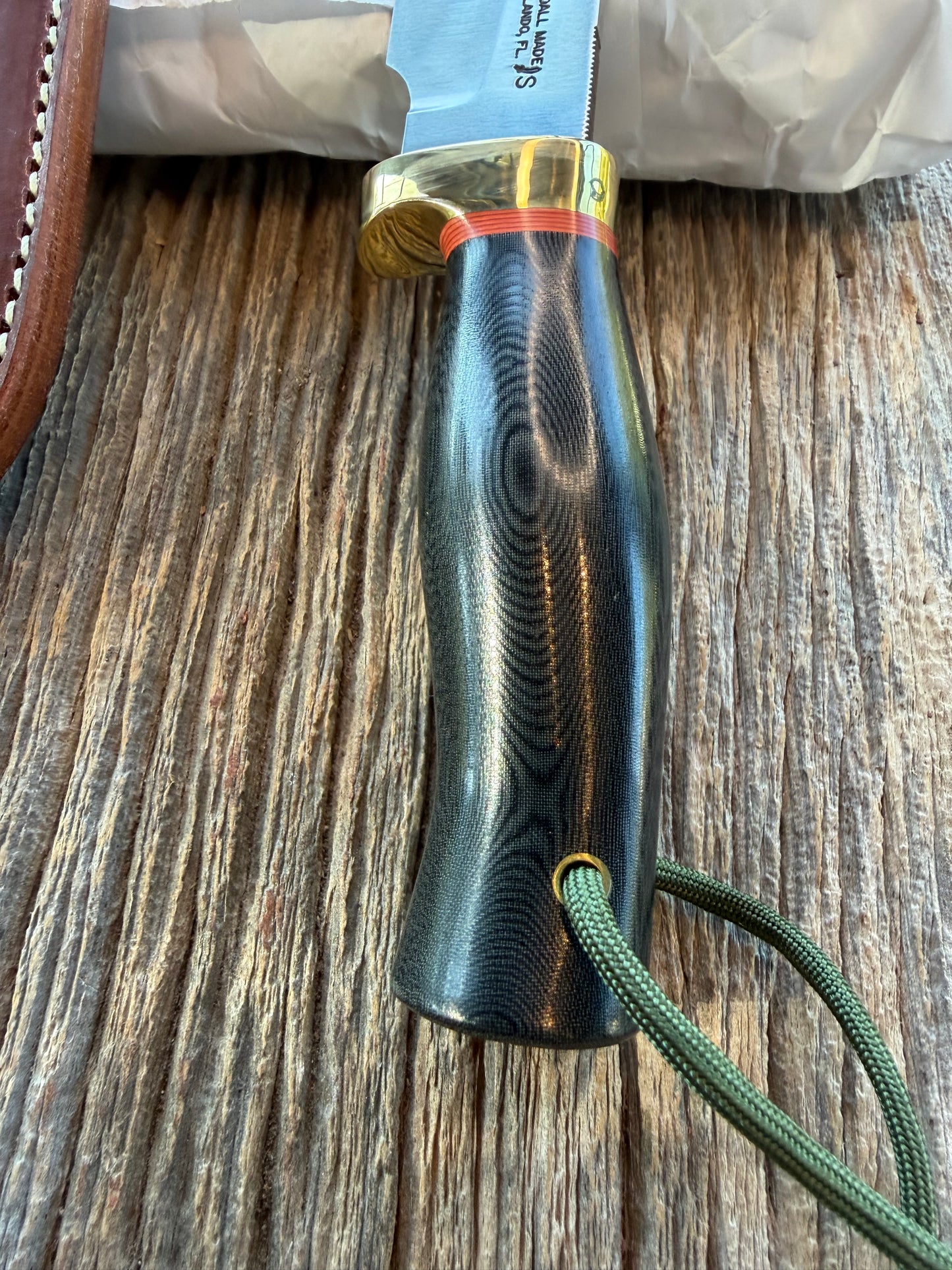 New in Paper Randall Chef’s Knife. Black Micarta in Brass with red spacers. Natural end, stainless steel blade and a lanyard.
