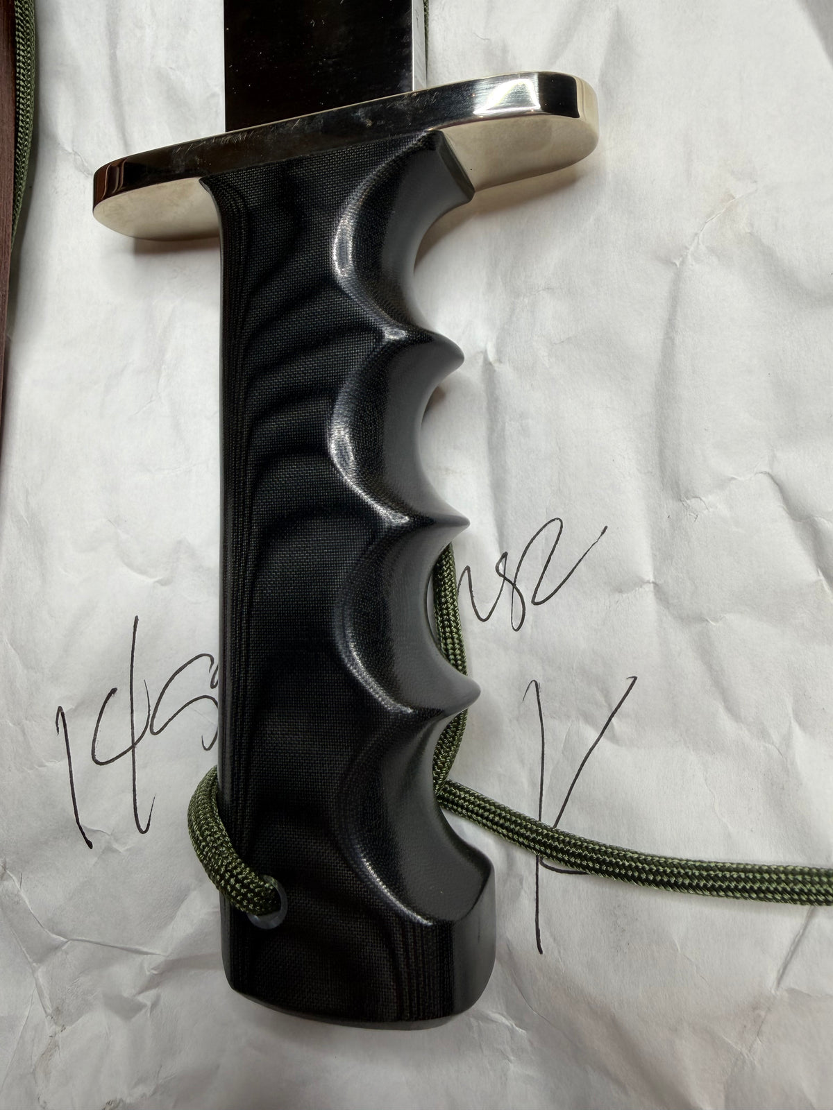 Randall Model 14-7.5 with a Black Micarta finger grooved handle. Stainless steel blade, Nickel double hilt brown leather sheath, Sawteeth, Lanyard.