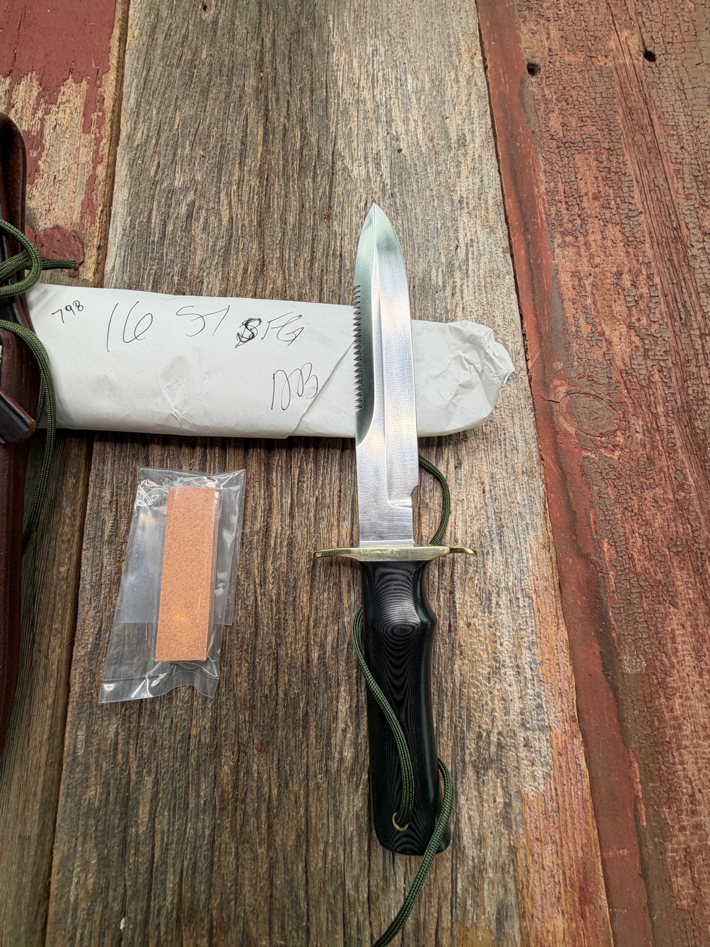 New in Paper Randall Model 16-7 Diver with a Black Micarta handle, Single finger grip , SS blade, Brass hilt, Sawteeth, Lanyard, Brown leather waxed sheath.